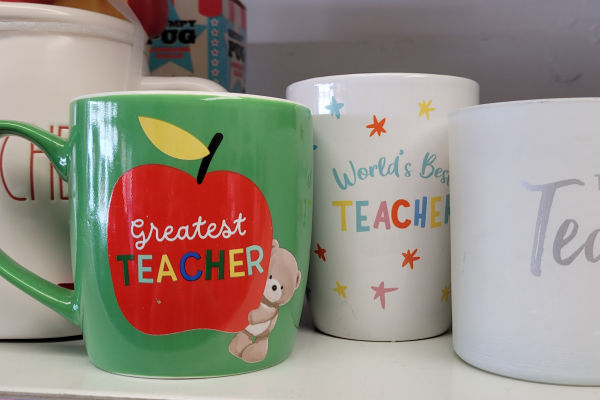 A collection of teacher gift mugs at a charity shop.